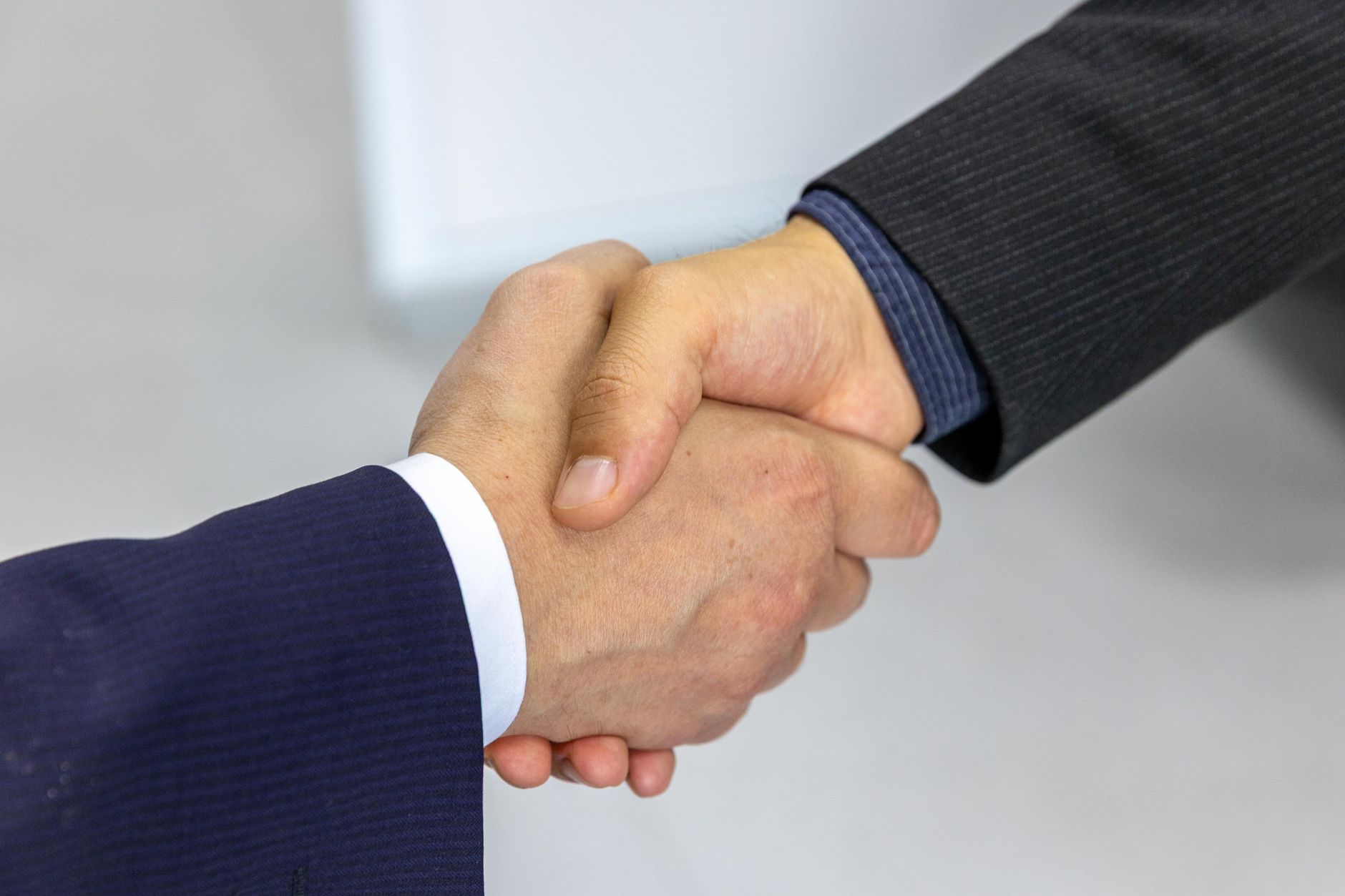 Aperto de mãos formal entre duas pessoas de terno